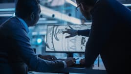 Die cast engineers designing with a blueprint on a screen